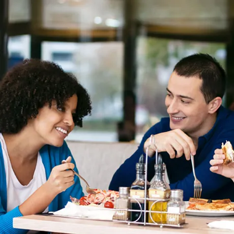 Two colleagues sharing a meal at an office dining table