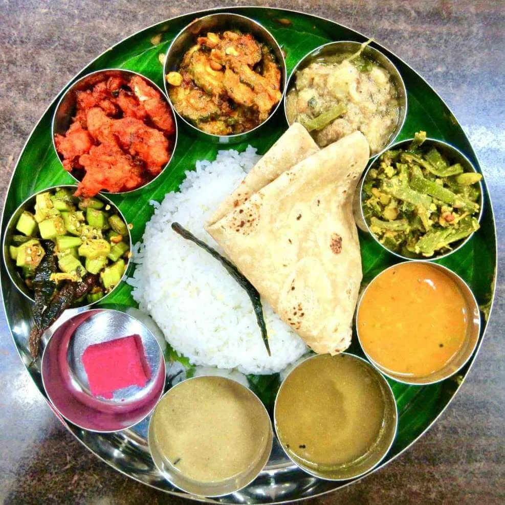 Steel thali with rice, roti, vegetables, and dal on a banana leaf